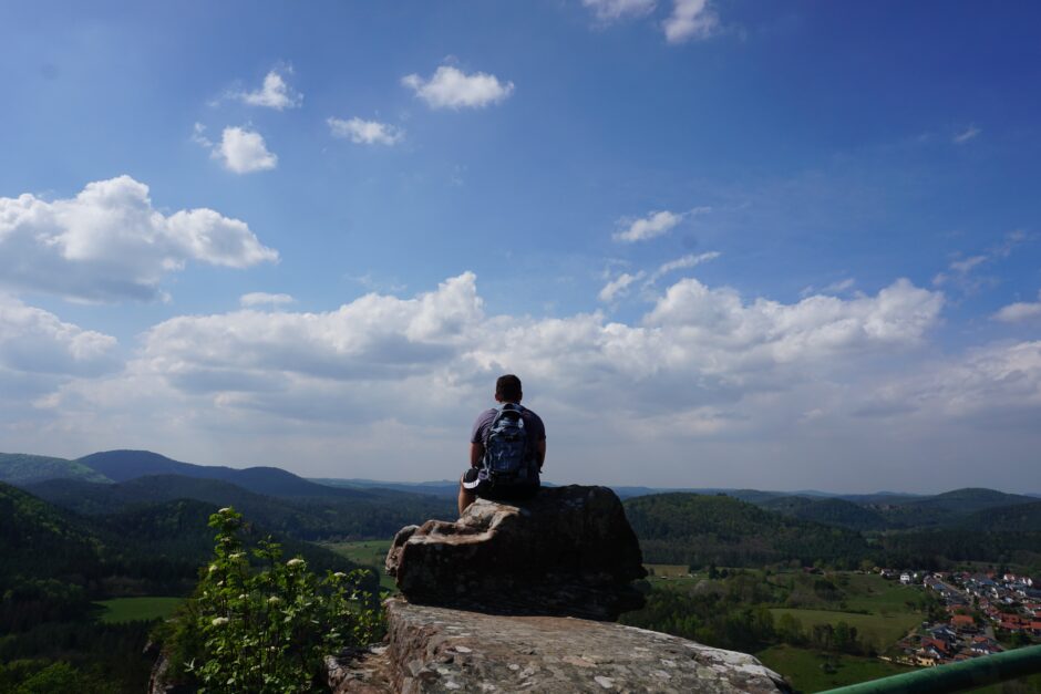 Wanderer sitzt auf Felsen und schaut über den Hunsrück